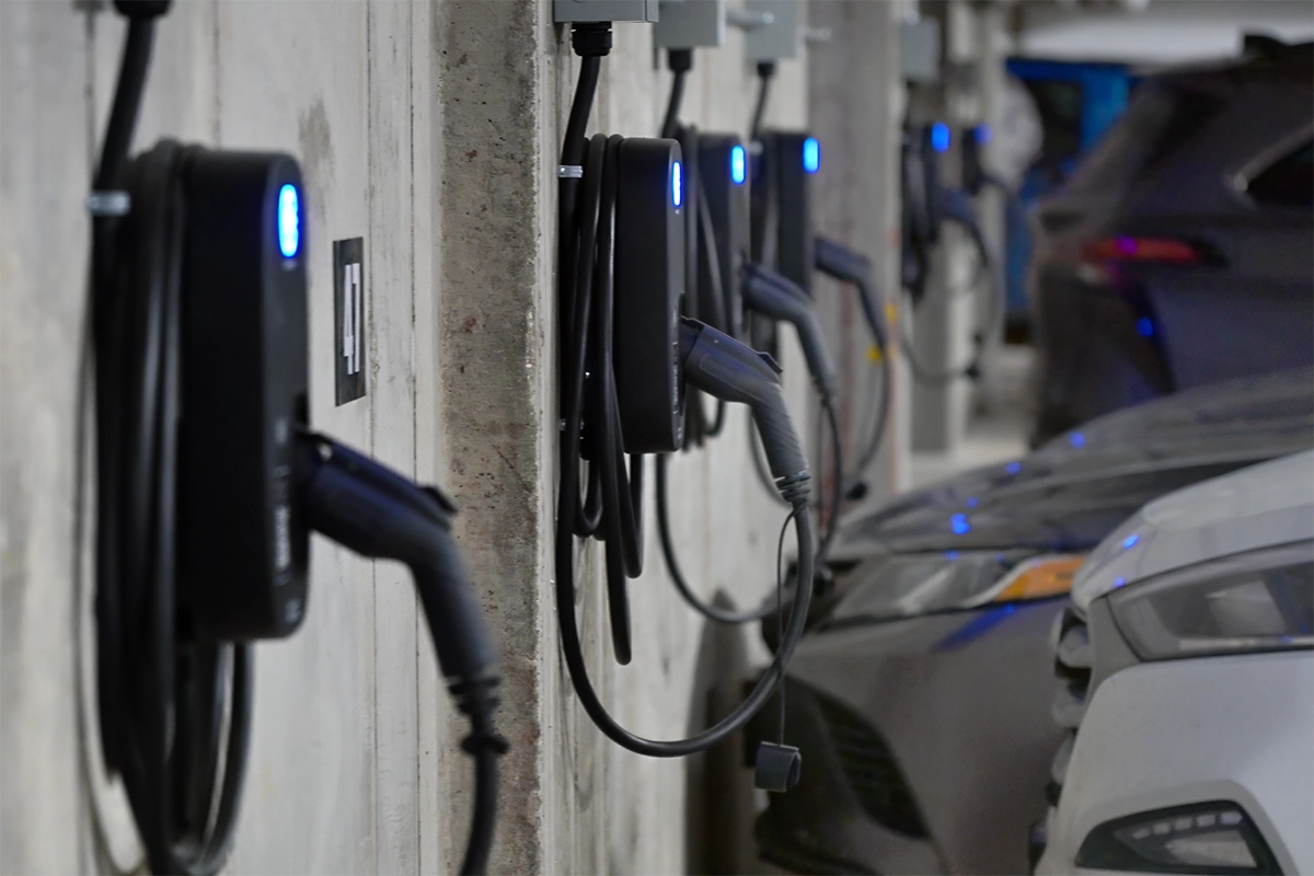 Plusieurs stations de recharge pour véhicules électriques Hypercharge Halo sont installées sur un mur en béton dans un stationnement, avec des câbles branchés dans les voitures voisines — une configuration idéale pour ceux qui apprennent à convaincre un conseil d’administration ou une association de copropriété d’installer une recharge pour VE. Several Hypercharge Halo electric vehicle charging stations are mounted on a concrete wall in a parking garage, with cables plugged into nearby cars—an ideal setup for those learning how to convince a condo board or HOA to install EV charging.