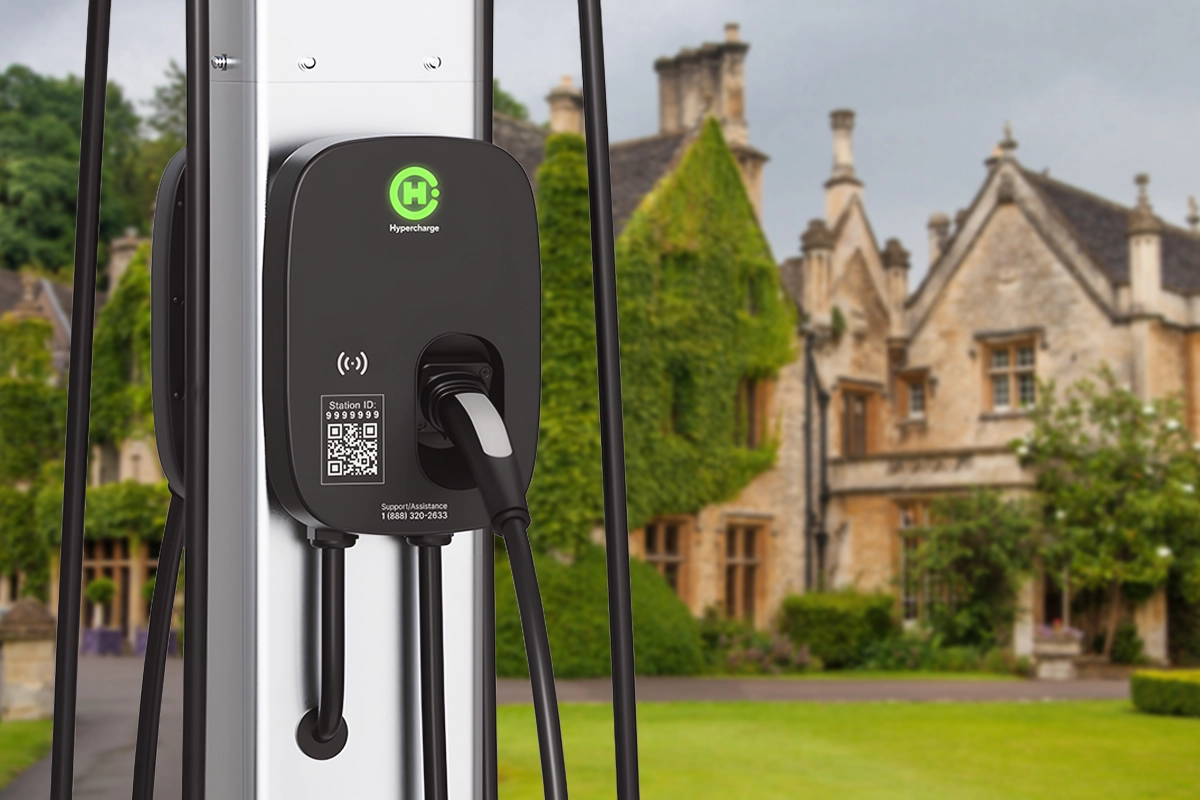 A black electric vehicle charging station is mounted on a pole, its cable plugged in. In the blurred background, a grand old stone mansion and green lawns highlight why premium hospitality needs EV charging for modern guests. Hypercharge Halo, Electric Vehicle Level 2 Charger mounted on a pole, its cable plugged in. In the blurred background, a grand old stone mansion and green lawns highlight why premium hospitality needs EV charging for modern guests.